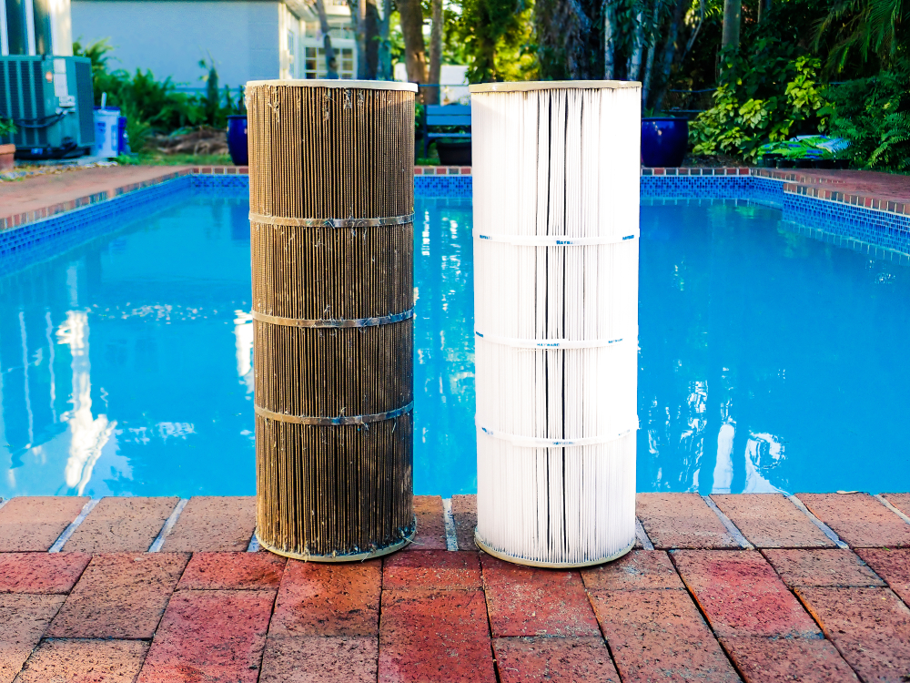 The Importance of Regular Pool Filter Cleaning and Replacement 1 Juxtaposition of a dirty reusable washable pleated reinforced polyester cartridge pool filter next to a clean filter, after routine maintenance cleaning. Pool surrounded by bricks in background.