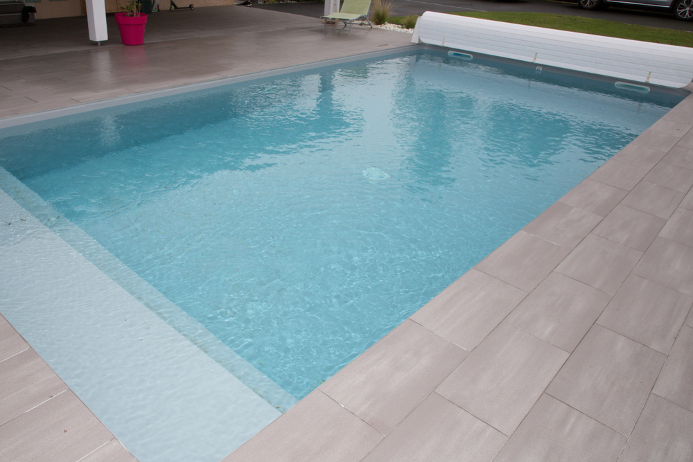 Common Pool Issues That Arise in Early Summer (and How to Fix Them) 1 swiming-pool in garden home with rigid pool cover rolled up on roller