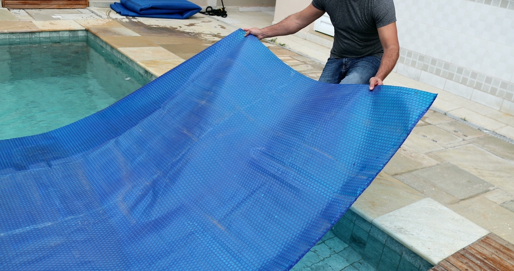 Man removing swimming pool cover and folding protector